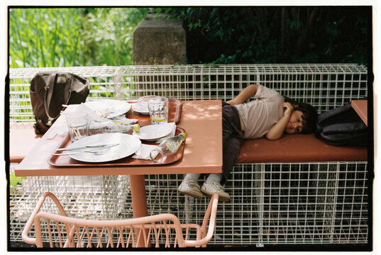 Child resting on bench after lunch outdoors