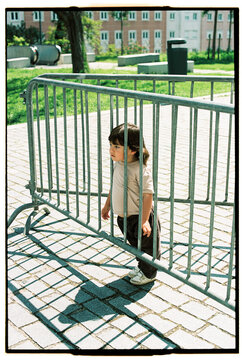 Child behind metal barrier in the street on sunny day