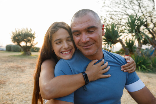 Smiling teenage girl hugs her happy dad 