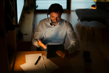 Man working late during online meeting using tablet
