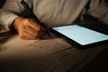 Person writing notes and planning work using digital tablet
