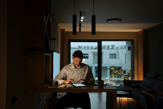 Man working late night from home office on tablet
