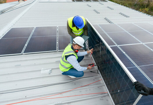 Workers installing solar panels on building roof