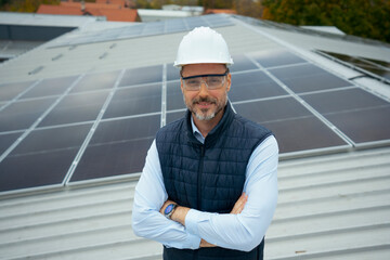 Engineer man on rooftop with solar panels smiling
