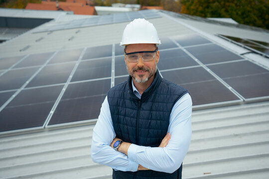 Engineer man on rooftop with solar panels smiling
