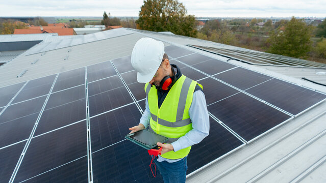 Technician inspecting solar panels on a building roof
