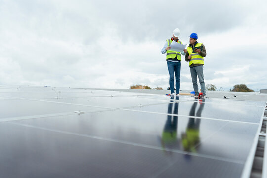 Engineers discussing plans on solar panel rooftop installation
