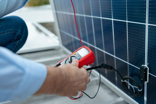 Technician checking solar panel performance with a multimeter on a roo