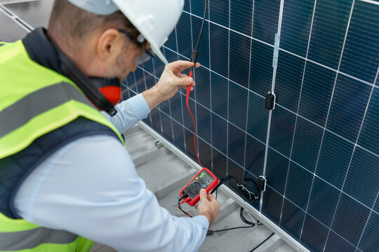Engineer checking solar panel performance with multimeter
