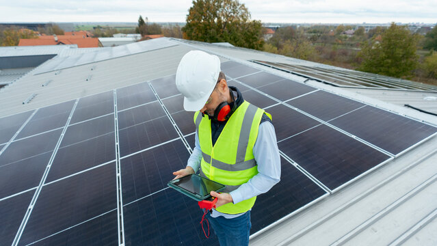 Technician inspecting solar panels at renewable energy rooftop install