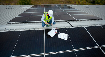 Technician inspecting solar panels on rooftop for renewable energy
