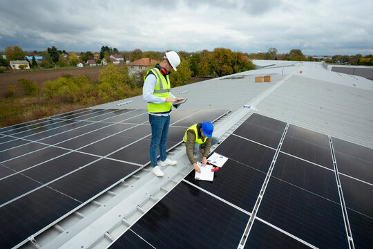 Engineers installing solar panels on rooftop for renewable energy
