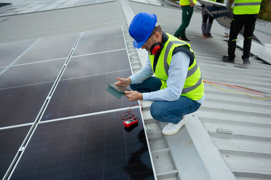 Technician analyzing solar panel performance on industrial rooftop
