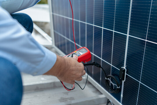 Technician checking solar panel performance with multimeter
