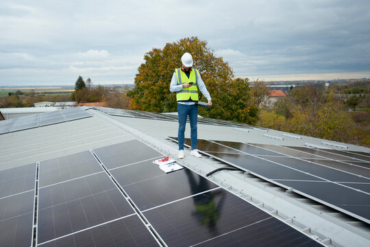 Worker performing maintenance on rooftop solar panels for renewable en