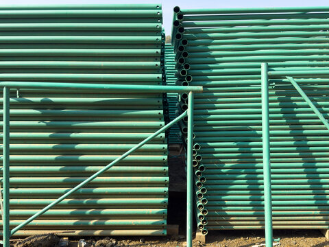 Stack of bundled green metal scaffolding pipes at construction site