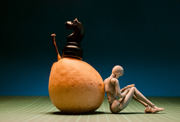 Chess piece and figure resting on a fruit