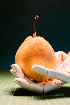 Robotic hand holding a ripe pear on a table