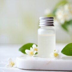 A small bottle of clear liquid adorned with delicate white flowers and green leaves, presented on a white marble surface with a soft, blurred background