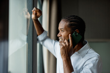 Smiling Businessman Talking on Phone by Window
