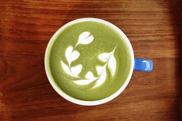 A cup of green tea matcha latte on wooden background                                                                         