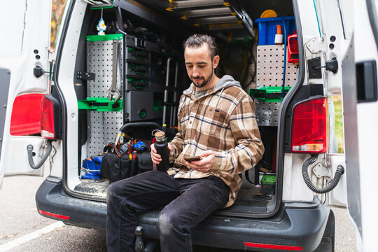 Technician Taking Break Sitting on Bumper of Service Van