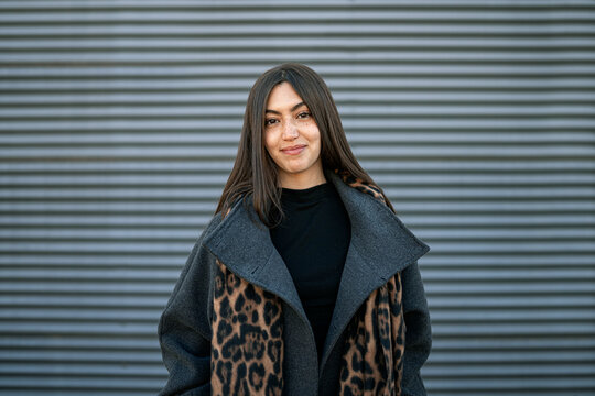 Young woman with freckles smiling wearing leopard print coat