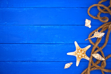 Seashells with rope and sand on blue wooden. Sea summer vacation background with space for the text. Top view