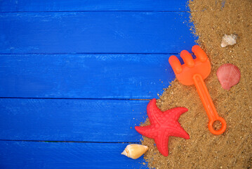 Beach toy for kids and sand on blue wooden. Sea summer vacation background with space for the text. Top view