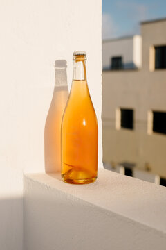 Bottle of sparkling wine lit by sunlight on the ledge of a rooftop