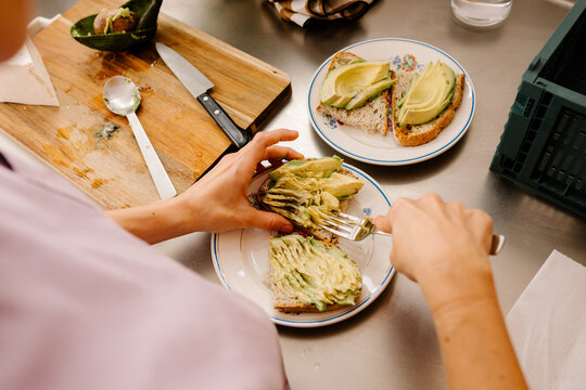 Unknown woman preparing avocado toast for breakfast