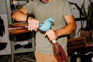 Anonymous winery worker hand-filling bottles