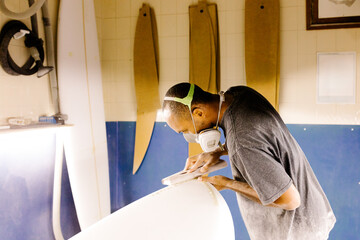 surfboard craftsman sanding a newly shaped board at his workshop
