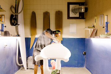 Handmade surfboard shaper using sandpaper to shape a new one