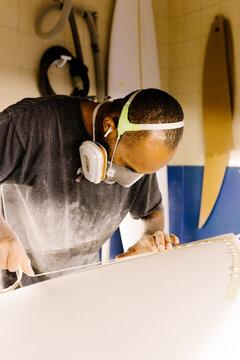 A surfboard shaper applying tape to outline guides