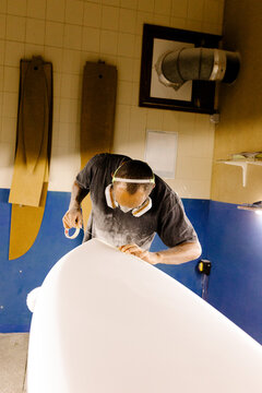 shaper using tape to mark lines while creating a new surfboard