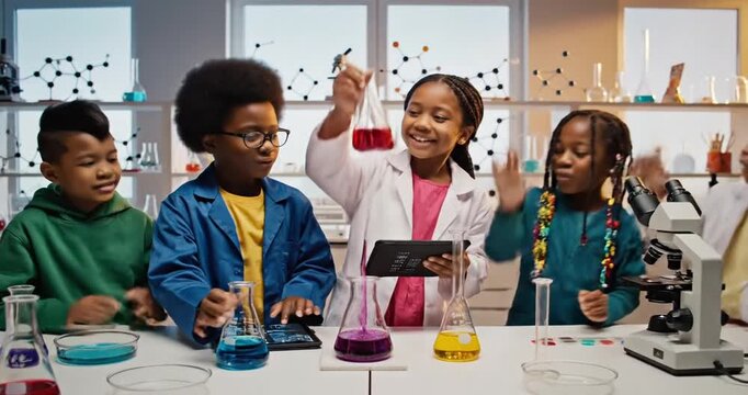 Group of children engaged in a science experiment in a bright laboratory with colorful liquids