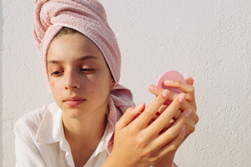 A pre-teen girl stuck on a pimple patch in the shape of a pink star. 