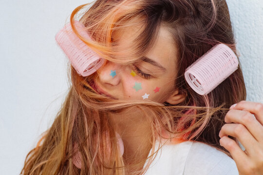 A girl stuck lots of pimple patches and put in curlers.