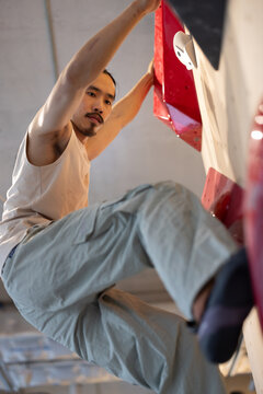 Climber on Indoor Bouldering Wall With Red Holds