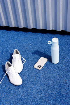 Minimal Fitness Gear Running Shoes, Bottle, and Phone on Blue Track