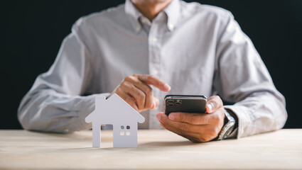 Man uses smart phone searching new home property online, finding real estate investment options with mobile app, planning future house acquisition, carefully considering purchase details