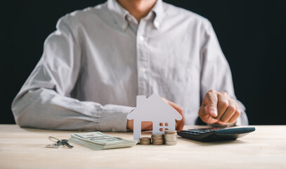 Person calculates home interest rate mortgage property loan money for house investment, showing financial planning with keys coins calculator on table