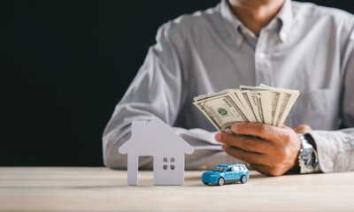 Man holds cash, planning home, car, property, house purchase, loan, insurance, making crucial real estate business concept investment decisions for new cars and estate