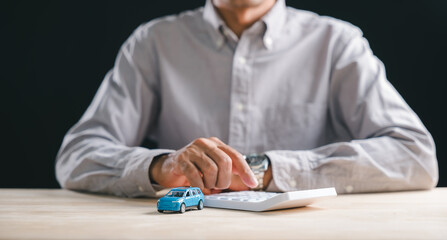 Insurance auto finance calculation, man uses calculator determining vehicle loan cost, planning money budget for buying or leasing new car model on smooth wooden desk