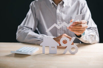 Person evaluates house property market, holding rising arrow showing growth, assessing real estate mortgage interest rates and loan percentage for successful investment