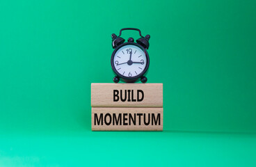Build momentum symbol. Wooden blocks with words Build momentum. Beautiful green background with alarm clock. Business and Build momentum concept. Copy space.