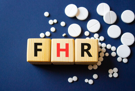 FHR symbol. Wooden cubes with words FHR Fetal Heart Rate. Beautiful deep blue background. Healthcare and Fetal Heart Rate concept. Copy space.