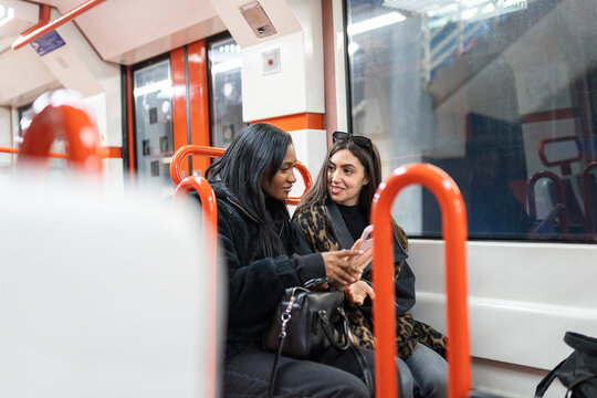 Diverse women friends talking on phone in subway