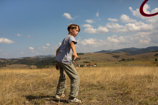Boy Playing frisbee Outdoors in a Grassy Field Under a Clear Sky